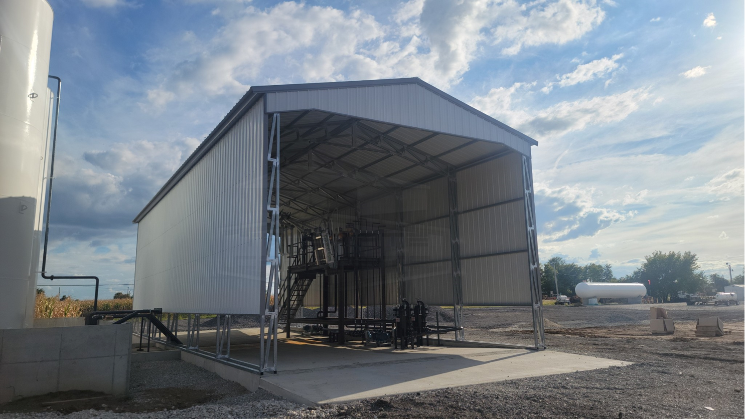 Large white commercial metal building on a concrete pad under a blue sky